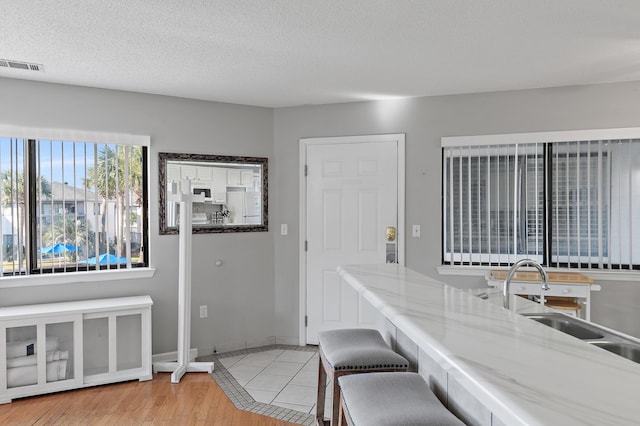 kitchen featuring a breakfast bar area, sink, white fridge, a textured ceiling, and light hardwood / wood-style floors