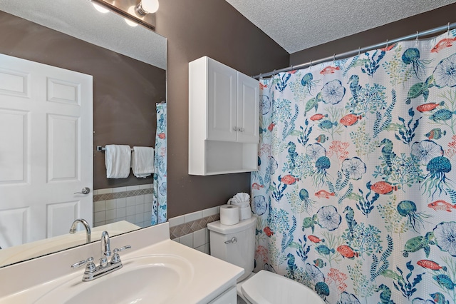 bathroom with toilet, a textured ceiling, walk in shower, and vanity