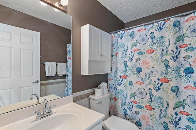 285 Payne St Unit 20B, Miramar Beach, FL 32550 - full bathroom with tile walls, toilet, a wainscoted wall, a textured ceiling, and vanity