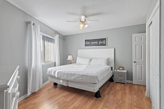 bedroom with light hardwood / wood-style floors, a closet, a textured ceiling, and ceiling fan