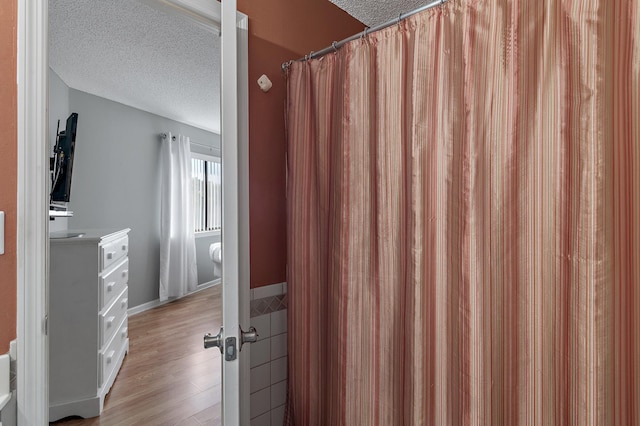 bathroom featuring hardwood / wood-style floors, a shower with shower curtain, and a textured ceiling