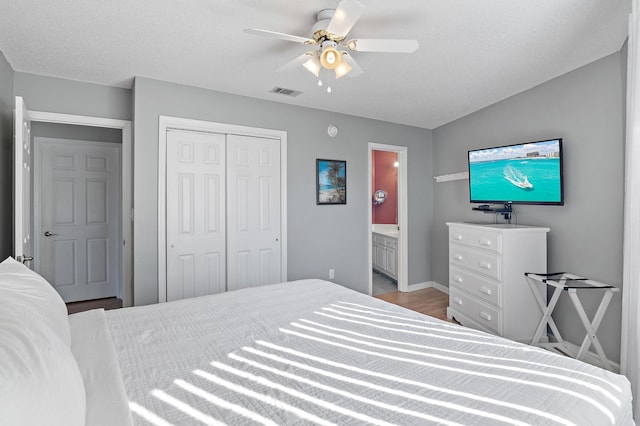 bedroom featuring light wood-type flooring, ensuite bath, a closet, ceiling fan, and vaulted ceiling