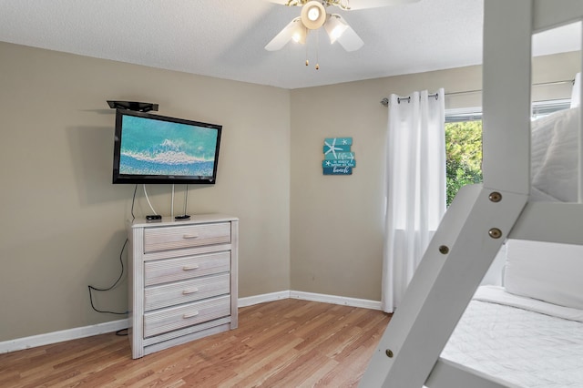 bedroom with light hardwood / wood-style flooring, a textured ceiling, and ceiling fan