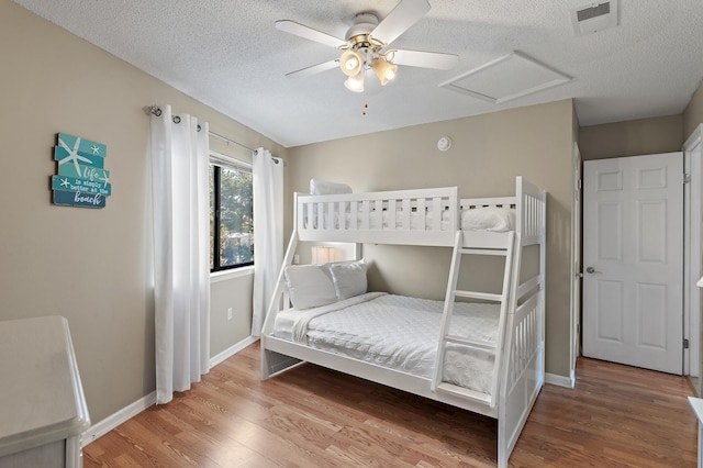 bedroom with a textured ceiling, wood-type flooring, and ceiling fan