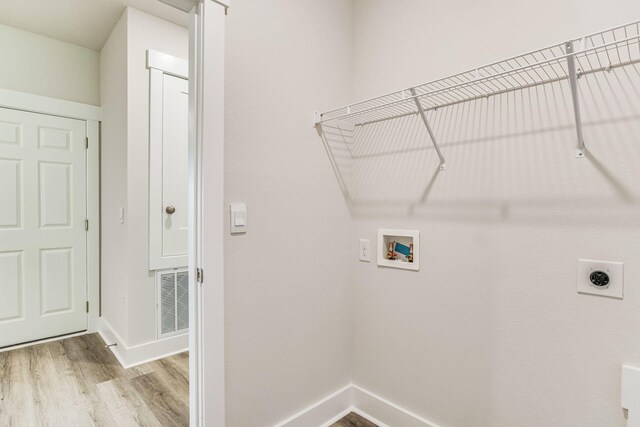 clothes washing area with hookup for an electric dryer, hookup for a washing machine, and light wood-type flooring