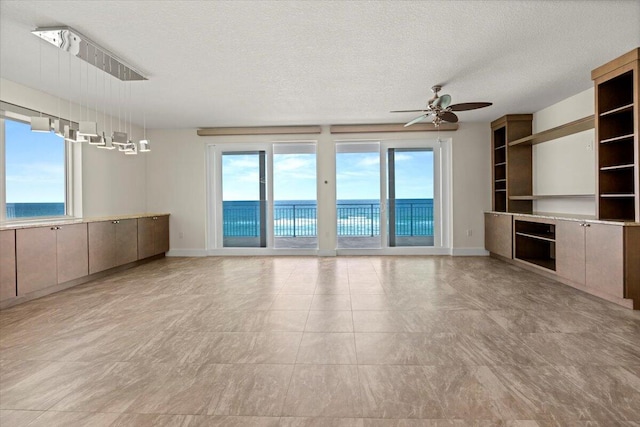 unfurnished living room with a water view, plenty of natural light, and a textured ceiling