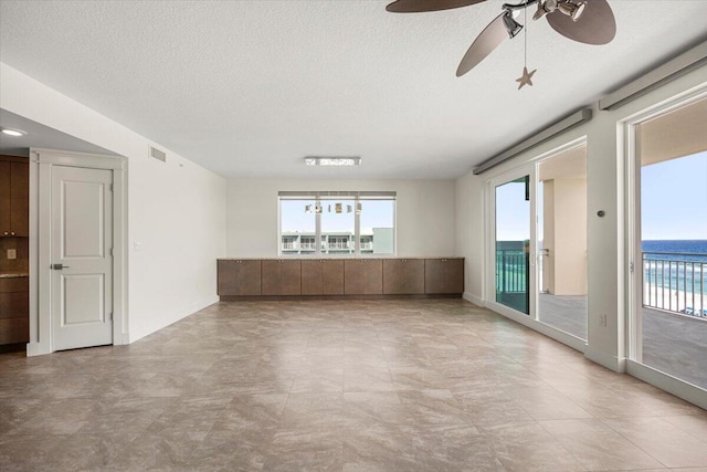 unfurnished room featuring a wealth of natural light, a water view, visible vents, and a textured ceiling