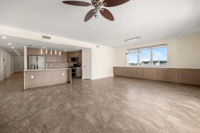 unfurnished living room with ceiling fan, a textured ceiling, visible vents, and a sink