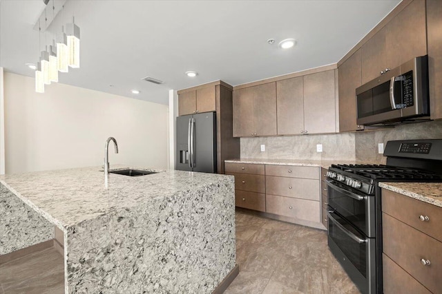 kitchen featuring appliances with stainless steel finishes, backsplash, a sink, and a kitchen island with sink