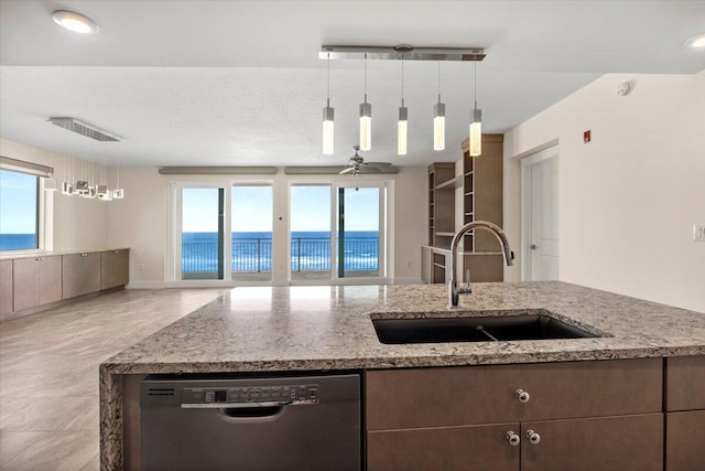 kitchen with light stone counters, decorative light fixtures, a water view, a sink, and dishwasher