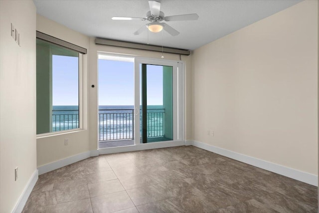 unfurnished room featuring a water view, a ceiling fan, and baseboards