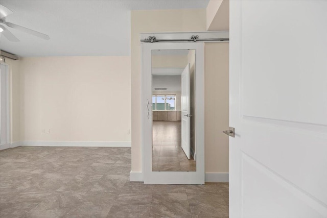 interior space with a barn door, baseboards, and ceiling fan