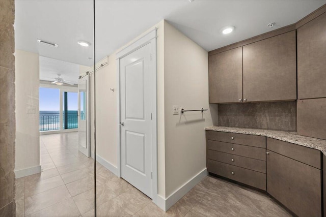 interior space with visible vents, a water view, backsplash, baseboards, and tile patterned floors