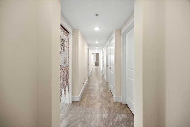 hallway featuring baseboards and recessed lighting