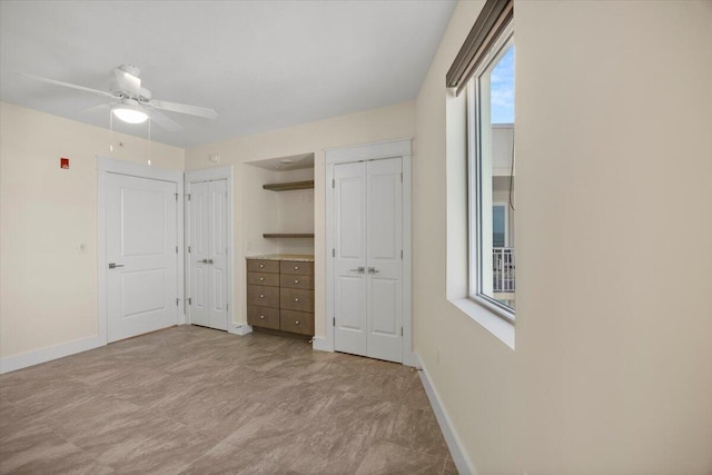 unfurnished bedroom with ceiling fan, baseboards, and multiple closets