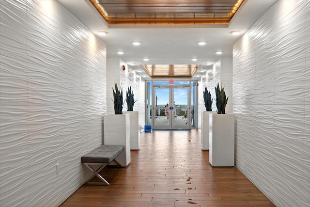 corridor with french doors, a tray ceiling, wood-type flooring, and recessed lighting