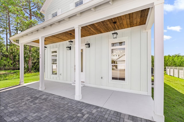 view of exterior entry featuring a patio area and a lawn