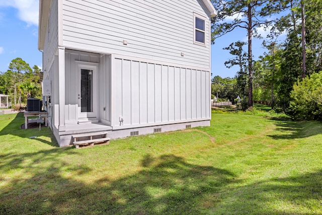 view of side of home with central air condition unit and a lawn