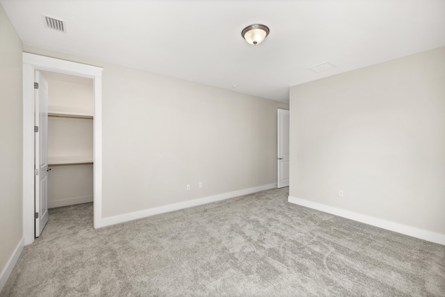 unfurnished bedroom with a spacious closet, a closet, and light colored carpet