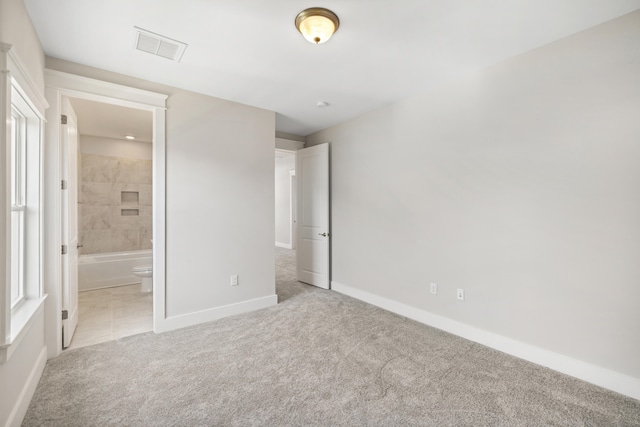 unfurnished bedroom with light carpet and ensuite bath