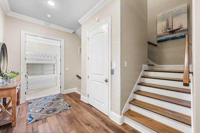 stairway with crown molding and wood-type flooring