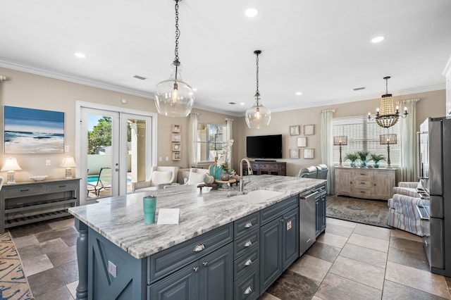 kitchen featuring an island with sink, light stone countertops, ornamental molding, stainless steel appliances, and sink