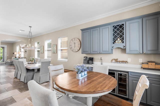 dining room with wine cooler, ornamental molding, and a chandelier