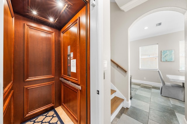 interior details with ornamental molding, elevator, and tile patterned floors