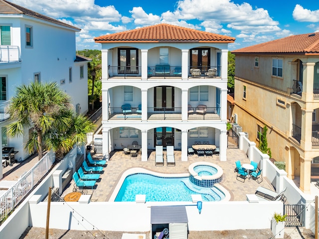 rear view of property with a balcony, a swimming pool with hot tub, and a patio area