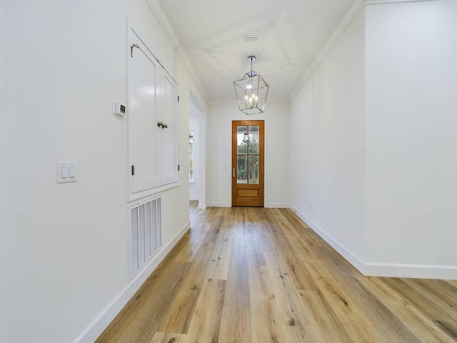 entryway featuring a notable chandelier, ornamental molding, and light wood-type flooring