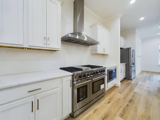 kitchen featuring wall chimney exhaust hood, ornamental molding, stainless steel appliances, light stone countertops, and white cabinets