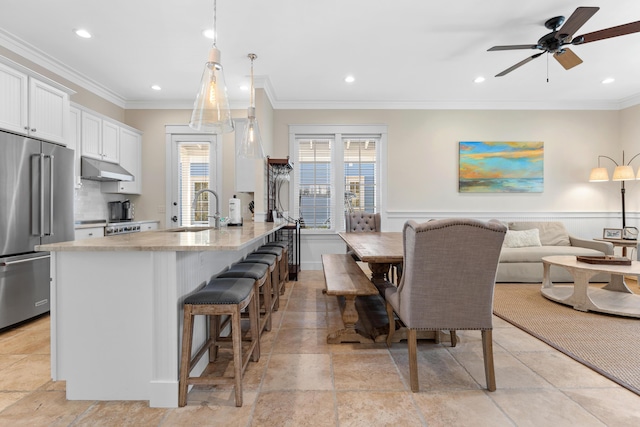 2448 Bungalo Ln, Miramar Beach, FL 32550 - kitchen with high quality fridge, a sink, under cabinet range hood, a breakfast bar area, and crown molding