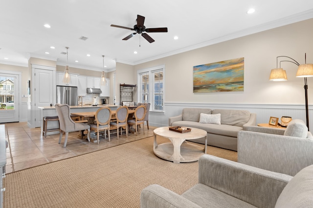 tiled living room featuring crown molding, sink, and ceiling fan