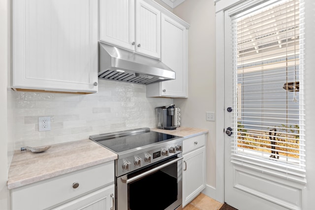 kitchen featuring backsplash, stainless steel range, white cabinets, and light tile patterned flooring