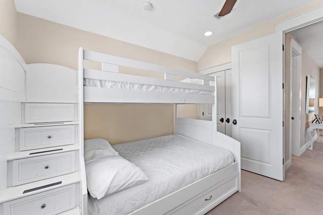 bedroom with lofted ceiling, a closet, light colored carpet, and ceiling fan