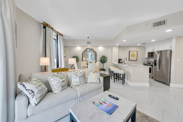 living room featuring sink and light tile patterned floors