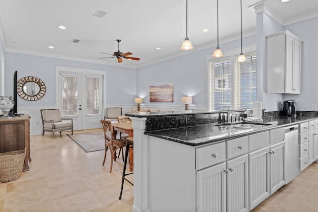 kitchen featuring sink, dishwasher, white cabinetry, decorative light fixtures, and crown molding