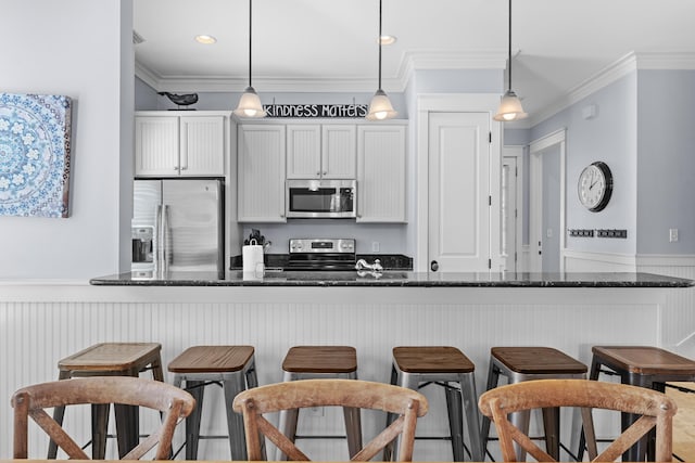 2452 Bungalo Ln, Miramar Beach, FL 32550 - kitchen featuring appliances with stainless steel finishes, wainscoting, a breakfast bar, crown molding, and pendant lighting