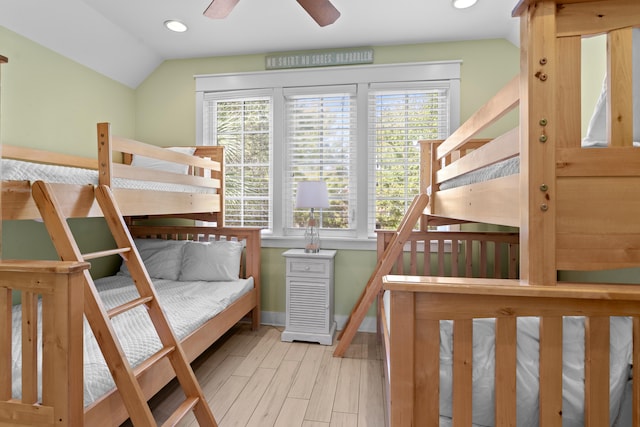 bedroom with vaulted ceiling, multiple windows, light hardwood / wood-style floors, and ceiling fan