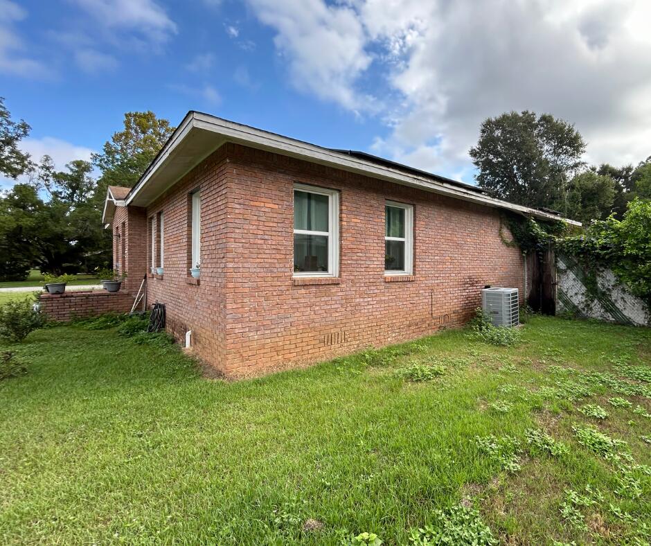 view of property exterior featuring central air condition unit, a lawn, and brick siding