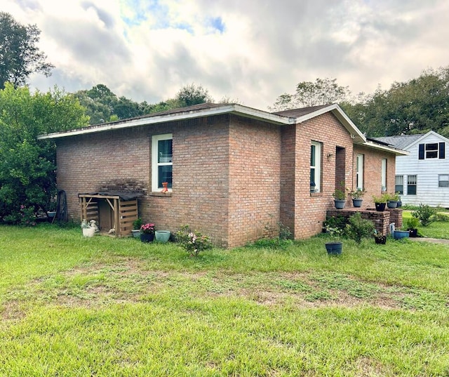view of side of property featuring brick siding and a yard