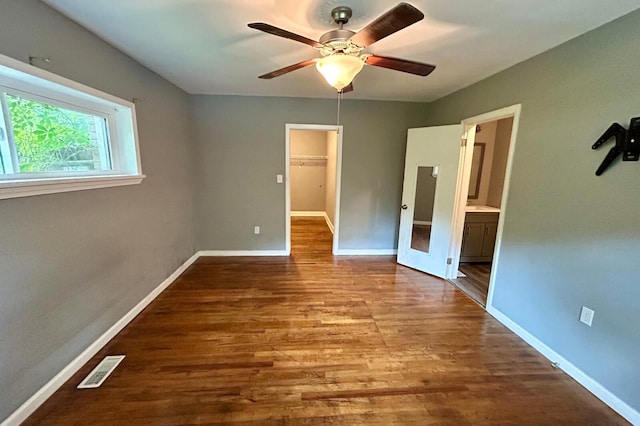297 Anderson St, Crestview, FL 32536 - unfurnished bedroom featuring wood finished floors, a spacious closet, baseboards, a closet, and connected bathroom