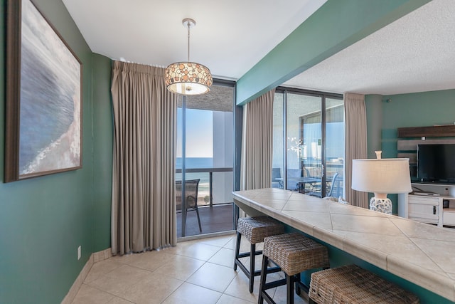 dining area with baseboards, a wall of windows, and light tile patterned floors