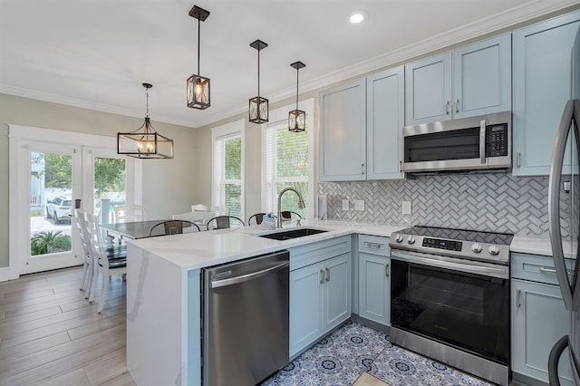 kitchen with pendant lighting, stainless steel appliances, sink, and kitchen peninsula