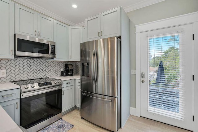 kitchen featuring backsplash, crown molding, appliances with stainless steel finishes, and light hardwood / wood-style flooring