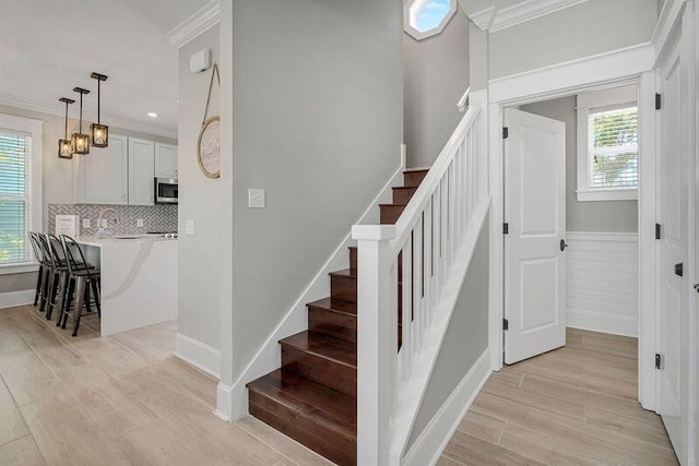 staircase with a wealth of natural light, ornamental molding, and hardwood / wood-style floors