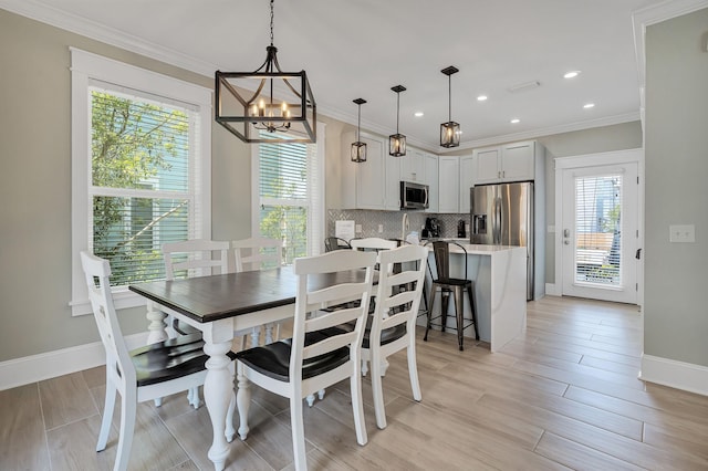 dining area featuring crown molding, light hardwood / wood-style flooring, an inviting chandelier, and plenty of natural light