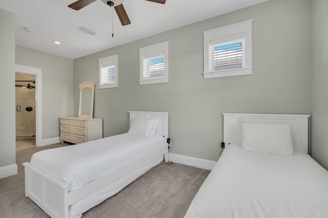 carpeted bedroom featuring ensuite bath, multiple windows, and ceiling fan