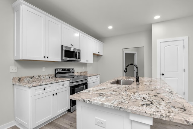 kitchen featuring a kitchen island with sink, sink, white cabinets, and stainless steel appliances