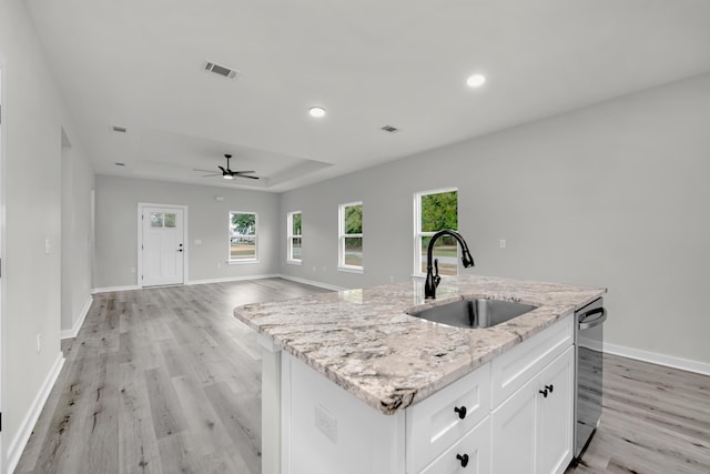 kitchen with light stone counters, ceiling fan, a kitchen island with sink, sink, and white cabinetry